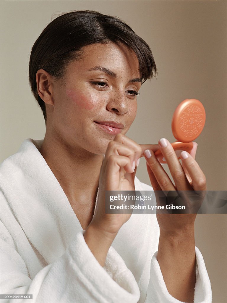 Young woman putting on make-up