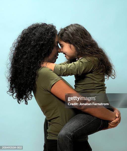 mother carrying daughter head to head, side view - dubbelgångare bildbanksfoton och bilder