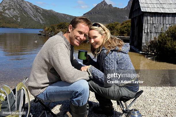 couple sitting on camping chairs, smiling, portrait - cradle mountain stock pictures, royalty-free photos & images