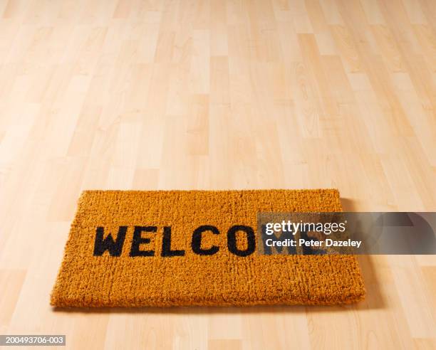 welcome doormat on wooden floor, close-up, elevated view - zerbino foto e immagini stock