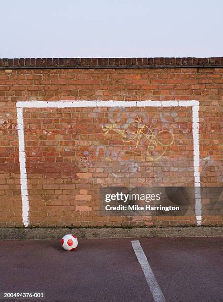 goal posts painted on playground wall, football on ground - palo della porta foto e immagini stock