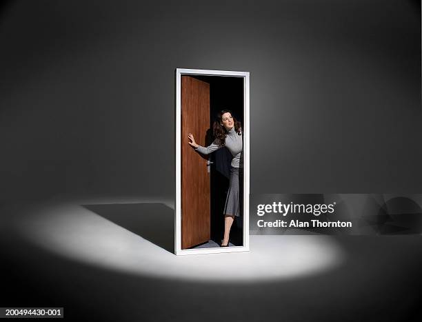 woman looking out of free standing doorway in spotlight - puerta fotografías e imágenes de stock