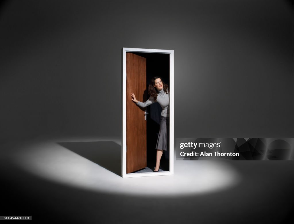 Woman looking out of free standing doorway in spotlight