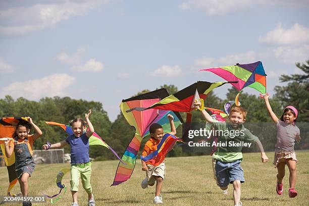 children holding kites above head, running outdoors - kite toy stock-fotos und bilder