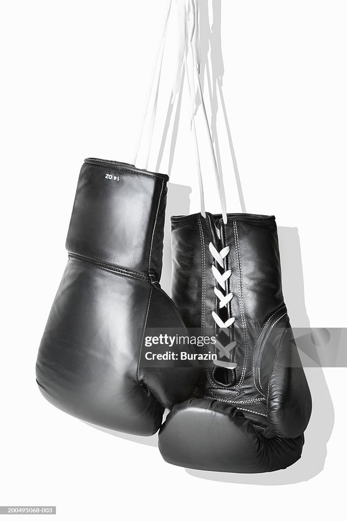 Boxing gloves hanging against white background, close-up