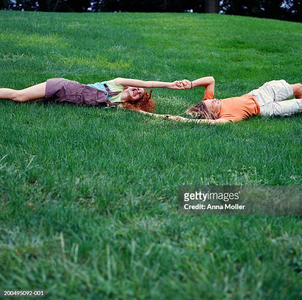 teenage couple (15-17) holding hands, rolling down hill - rollup photos et images de collection