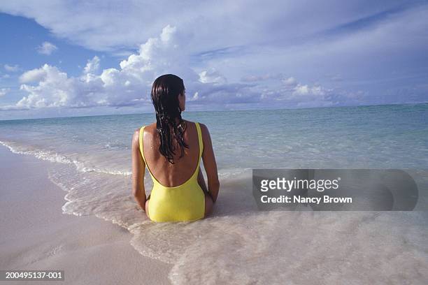 woman wearing swimsuit on beach, rear view - one piece swimsuit stock pictures, royalty-free photos & images