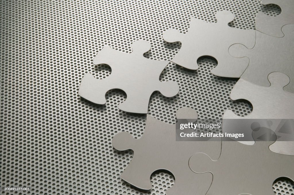 Metal jigsaw pieces on perforated aluminum