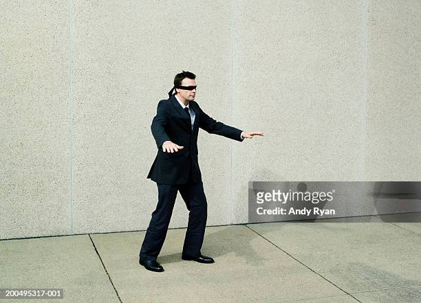 businessman wearing blindfold walking aimlessly on sidewalk - 目隠し ストックフォトと画像