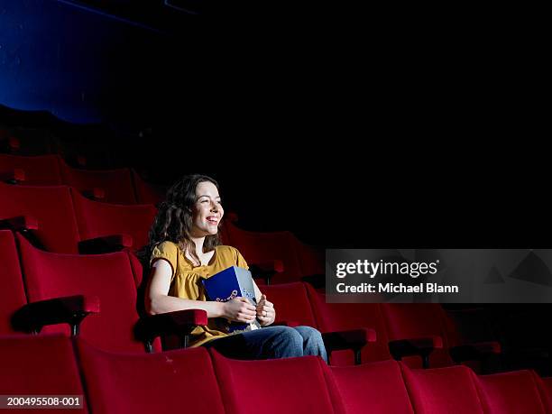young woman sitting in empty cinema, laughing - michael young theatre stock pictures, royalty-free photos & images