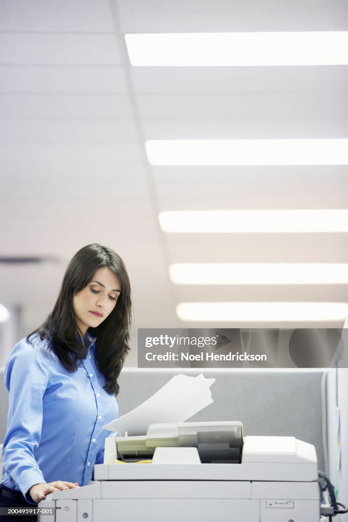 Young businesswoman using photocopier, side view