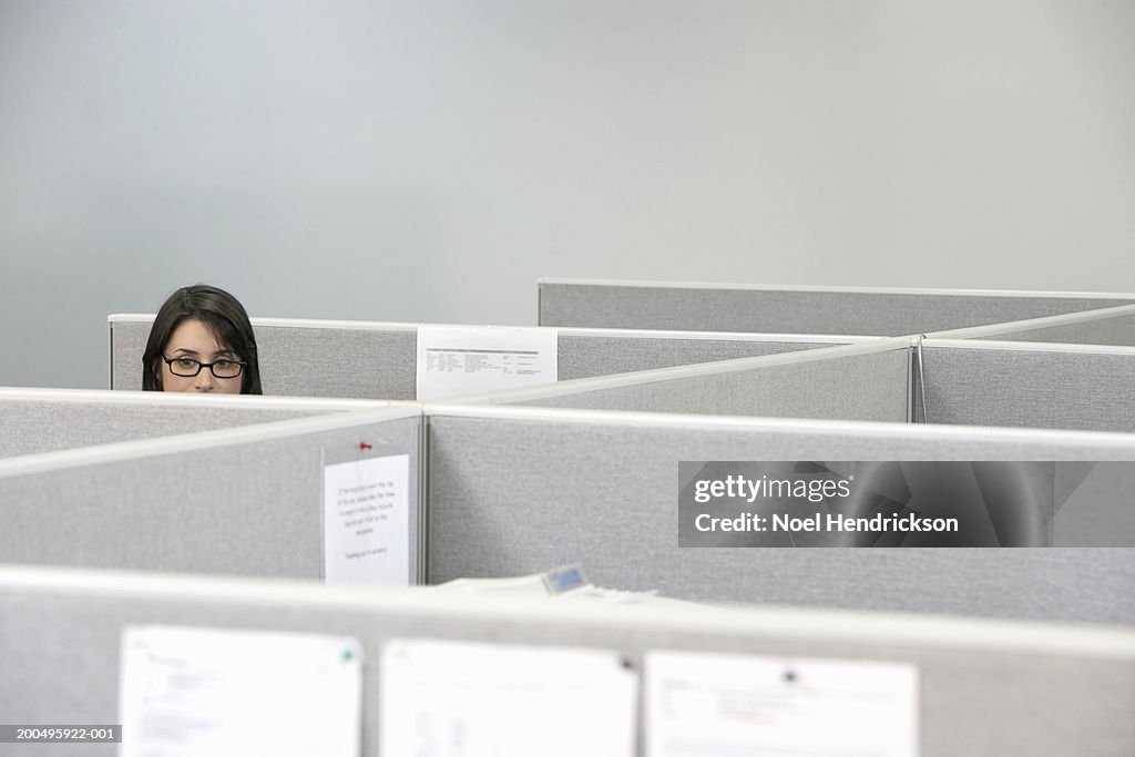 Young businesswoman sitting in cubicle, high section