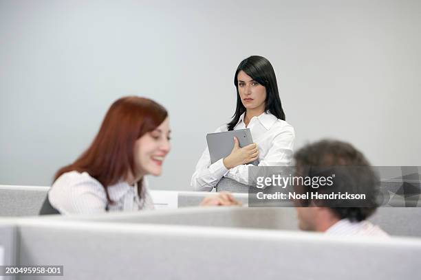 businesswoman watching two coworkers talking over cubicle wall - envy fotografías e imágenes de stock