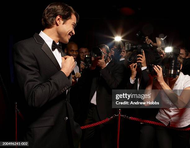 male celebrity in tuxedo being photographed by paparazzi at event - estreno fotografías e imágenes de stock