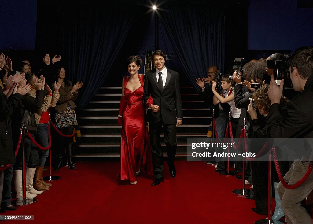 Celebrity couple in evening wear walking on red carpet