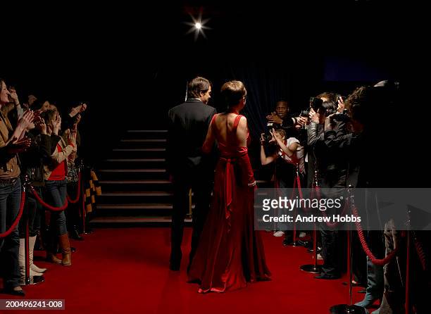 celebrity couple in evening wear walking on red carpet, rear view - red carpet stock-fotos und bilder
