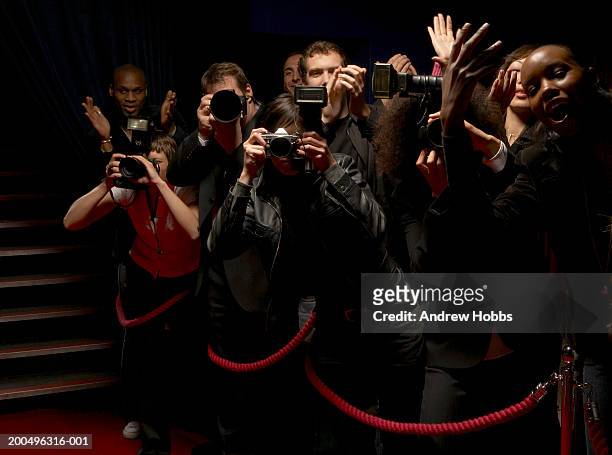 paparazzi and excited fans standing behind rope barrier on red carpet - red carpet event stock-fotos und bilder