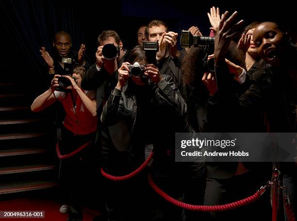 paparazzi and excited fans standing behind rope barrier on red carpet - paparazzi photos et images de collection