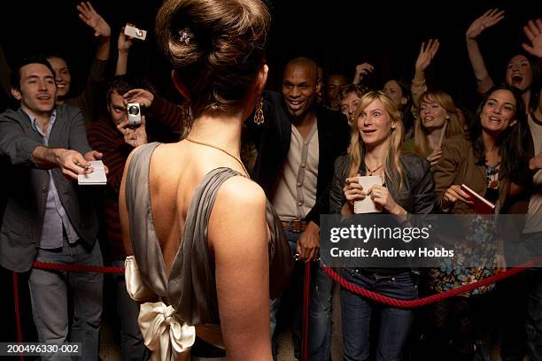 female celebrity in evening dress talking to fans behind rope barrier - celebrities stockfoto's en -beelden