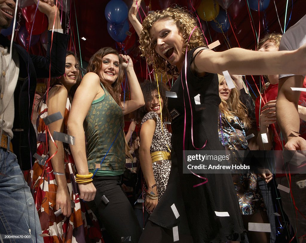 Young women disco dancing on busy dance floor, smiling, low angle view