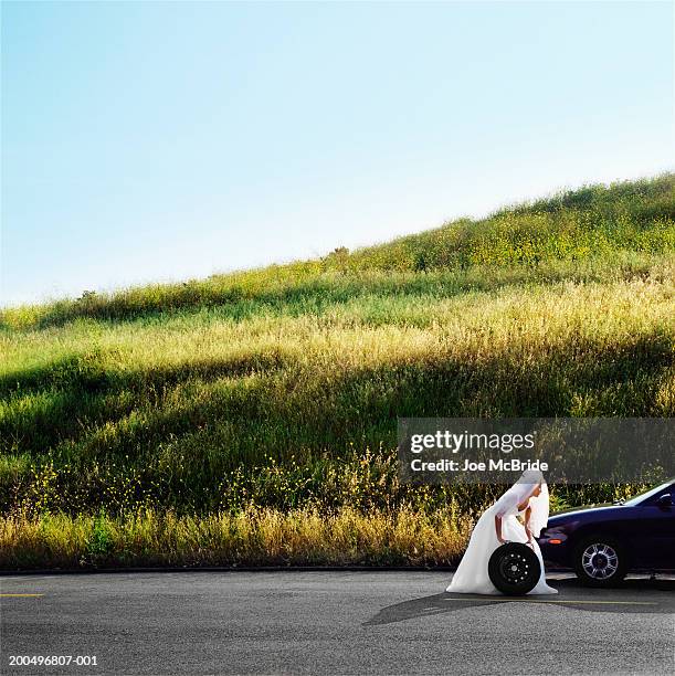 bride rolling car wheel on side of road, side view - vehicle breakdown bildbanksfoton och bilder