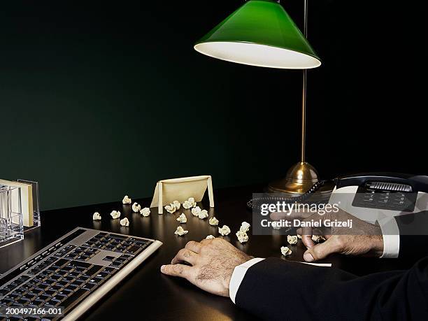 man flicking screwed up paper on desk by keyboard - wasting time stock pictures, royalty-free photos & images