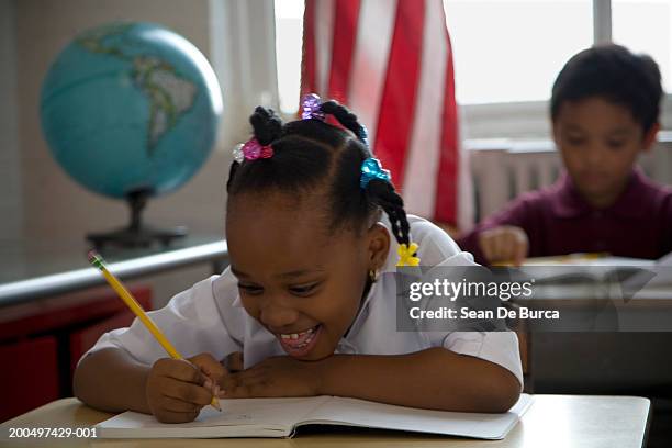 schoolchildren (5-8) writing at desks - écolière photos et images de collection