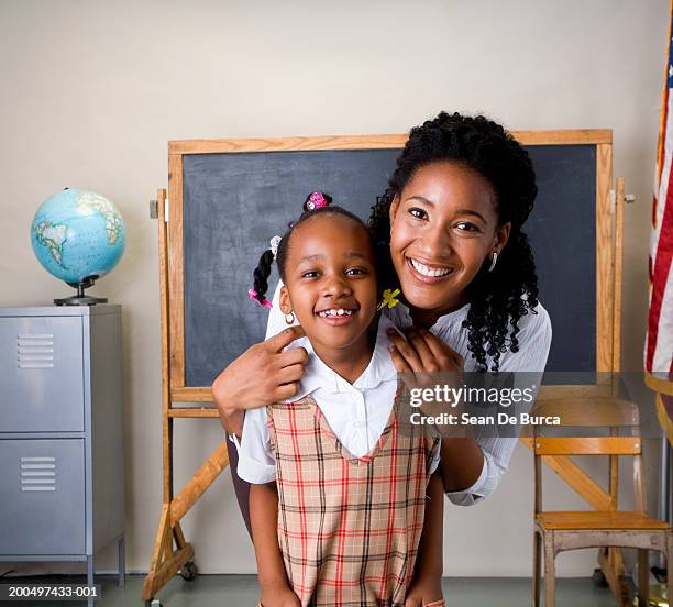 schoolgirl (5-7) and teacher smiling, portrait - two female teachers blackboard stockfoto's en -beelden