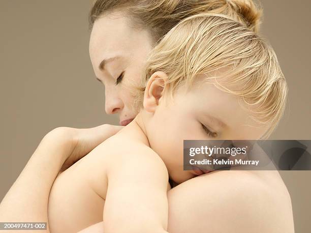 mother holding sleeping baby boy (9-12 months), close-up - baby studio shot stock pictures, royalty-free photos & images