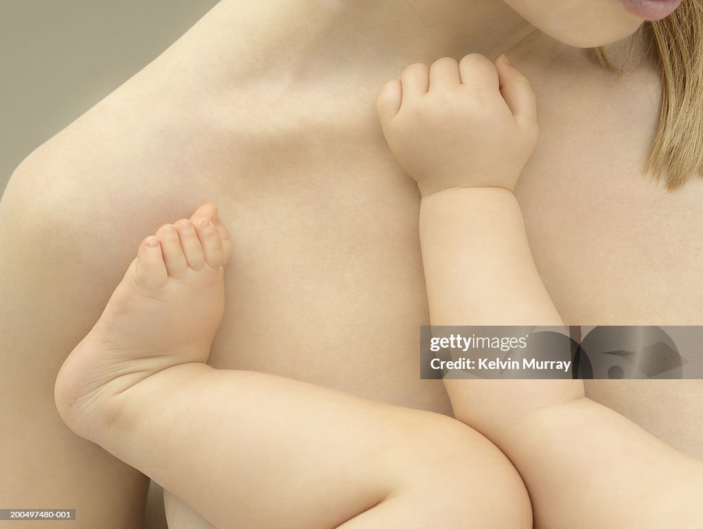 Mother holding baby boy (9-12 months), close-up, mid section