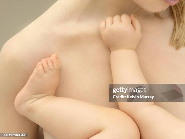 mother holding baby boy (9-12 months), close-up, mid section - blote jongens stockfoto's en -beelden