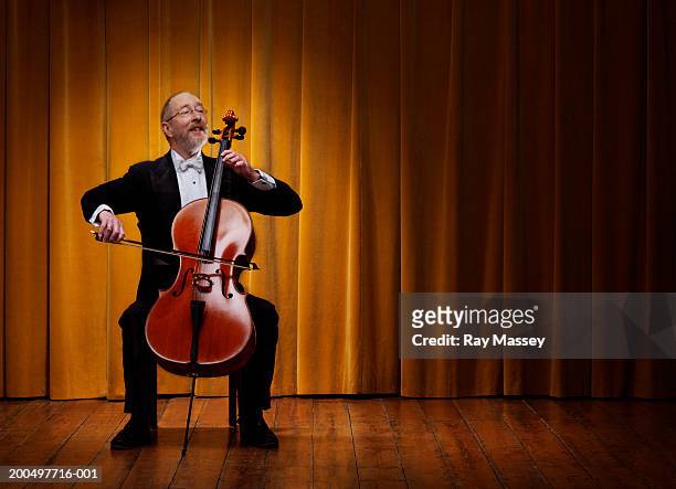 mature cellist playing on stage infront of curtains - cello - fotografias e filmes do acervo