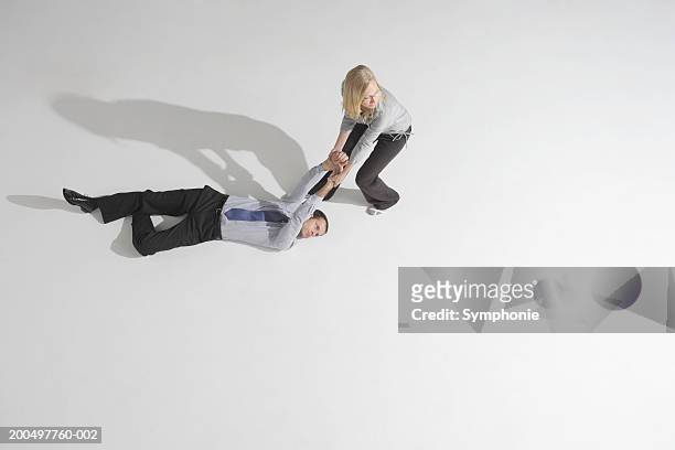 businesswoman dragging male colleague across floor, elevated view - professional drag stock pictures, royalty-free photos & images