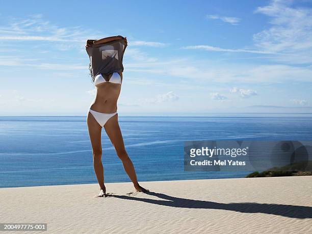 woman standing on beach taking off dress over head - beach dress stock pictures, royalty-free photos & images