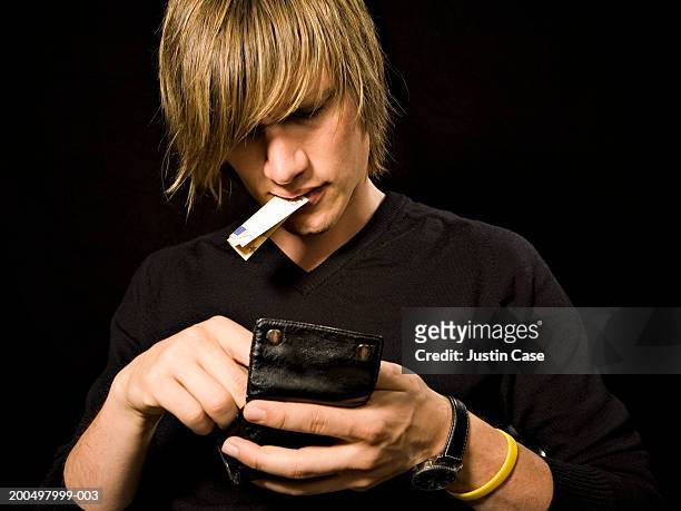 young man pulling money out of his wallet - searching mess stock pictures, royalty-free photos & images