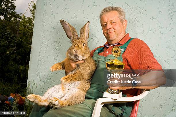 man holding large rabbit and trophy, outside - nur erwachsene stock-fotos und bilder