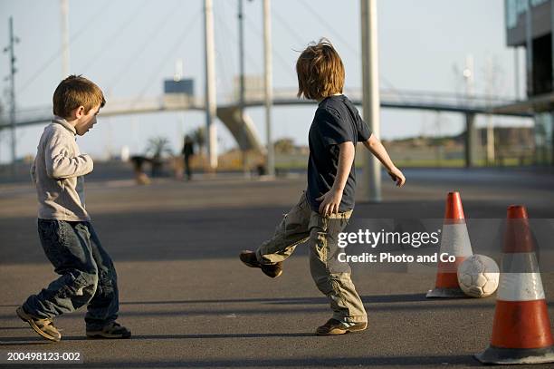 two boys (4-5) playing football in street - street football stock-fotos und bilder