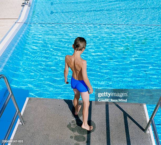 boy (8-9) standing on diving board over swimming pool - vertigo stock pictures, royalty-free photos & images