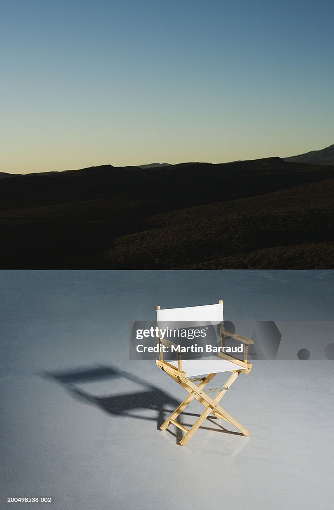Director's chair on platform at down, mountains in background