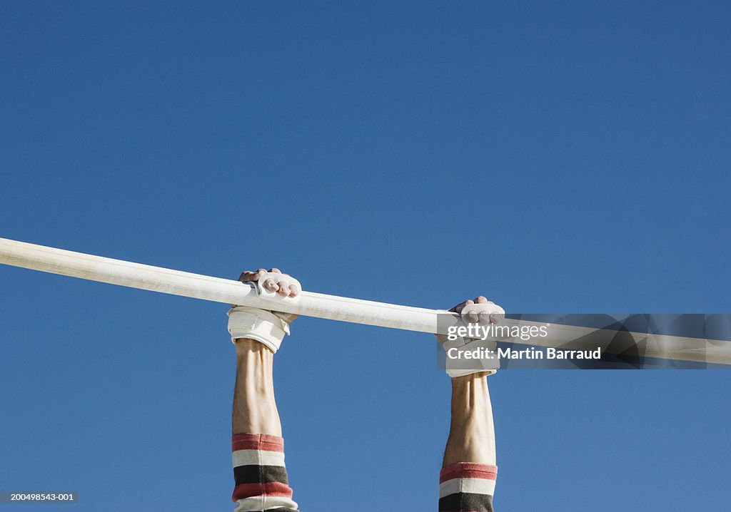 Gymnasts holding on to bar, low angle view