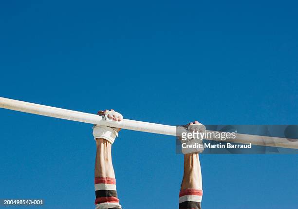 gymnasts holding on to bar, low angle view - brug turntoestel stockfoto's en -beelden