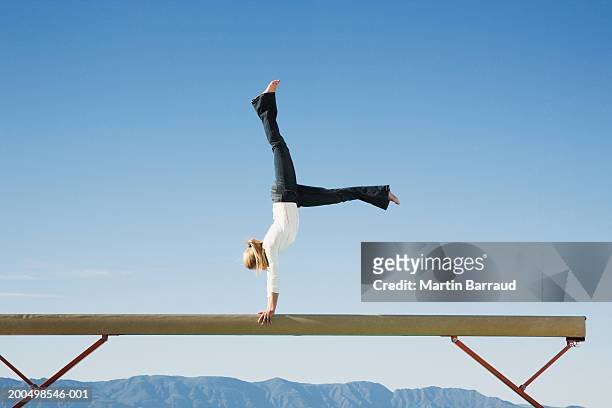 female gymnast performing on balance beam, side view - poutre photos et images de collection