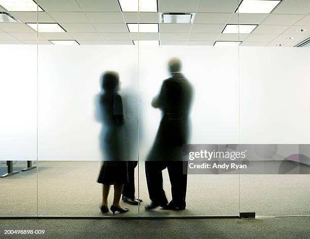 three colleagues standing behind frosted glass in office, talking - verre dépoli photos et images de collection