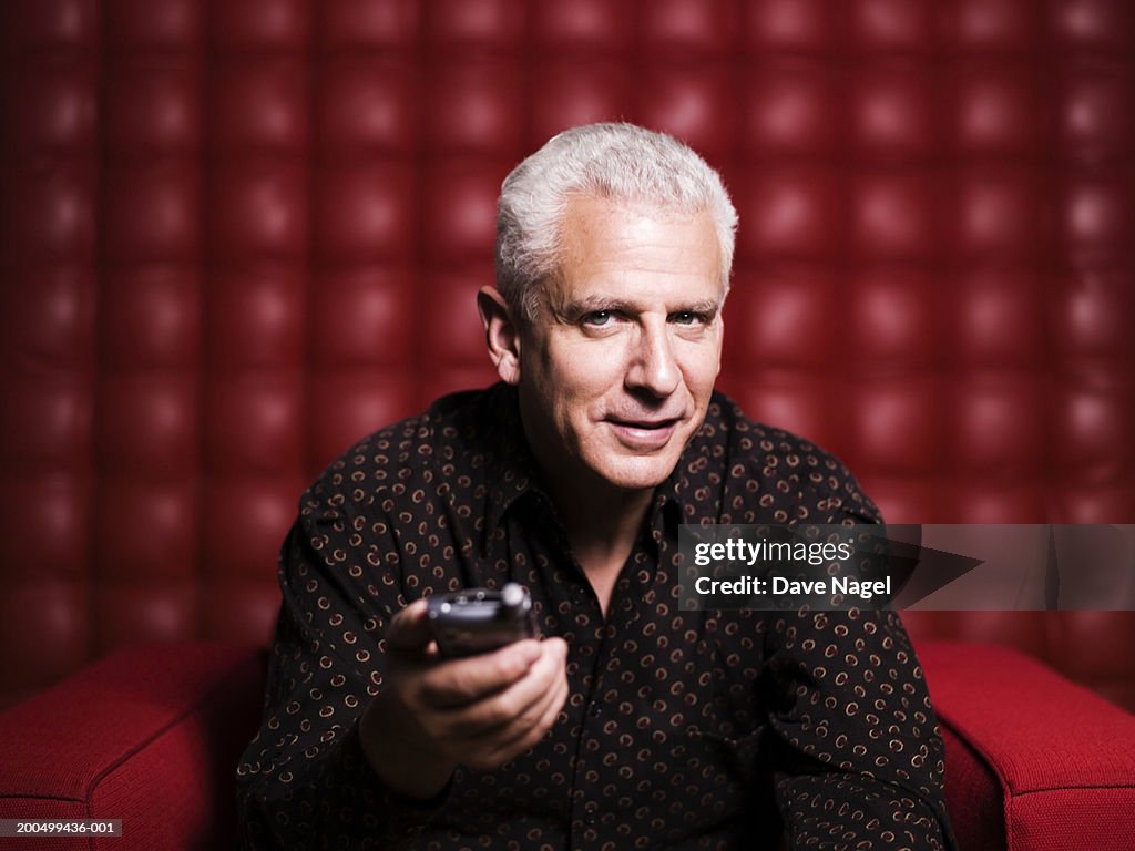 Mature man holding remote control, portrait