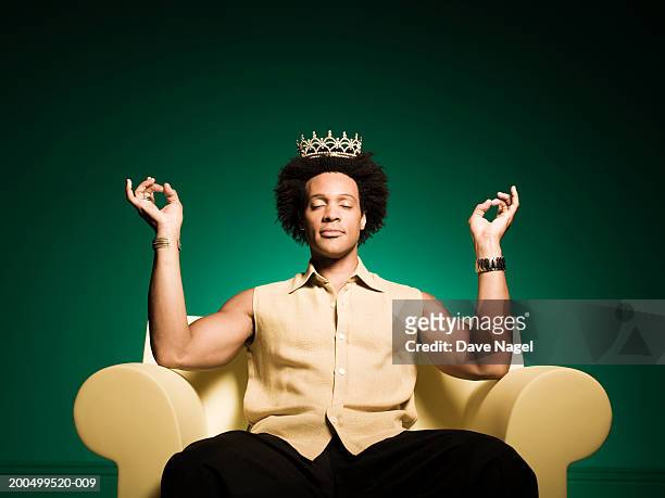 man meditating in armchair, wearing tiarra - krone kopfbedeckung stock-fotos und bilder