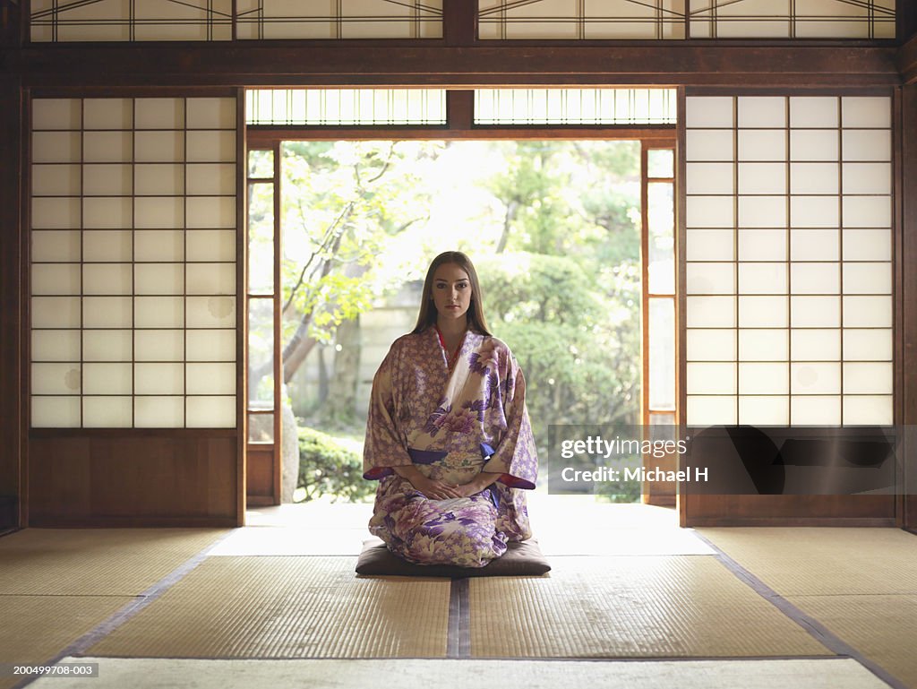 Japan, Tokyo, young woman in kimono kneeling on tatami mat, portrait