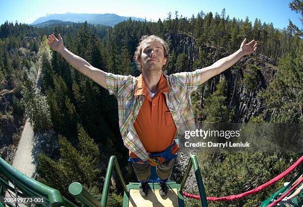 young man standing on bungee jump platform, (wide angle) - bunjee jumping stock-fotos und bilder