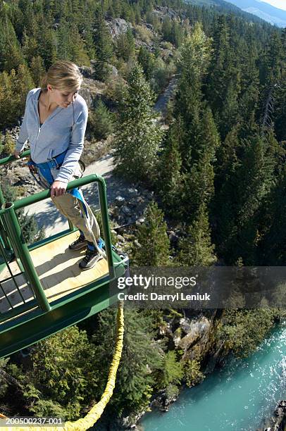 young woman on edge of bungee platform, looking down, (wide angle) - woman bungee jumping stock pictures, royalty-free photos & images