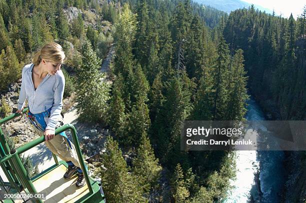 young woman on edge of bungee platform, looking down, (wide angle) - bungee jump - fotografias e filmes do acervo