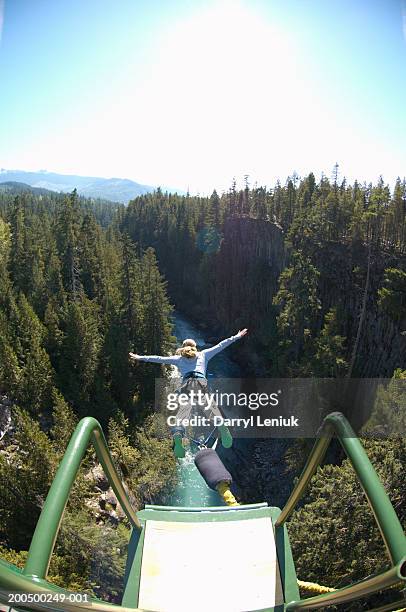 young woman bungee jumping, elevated view, (wide angle) - bungee stock pictures, royalty-free photos & images